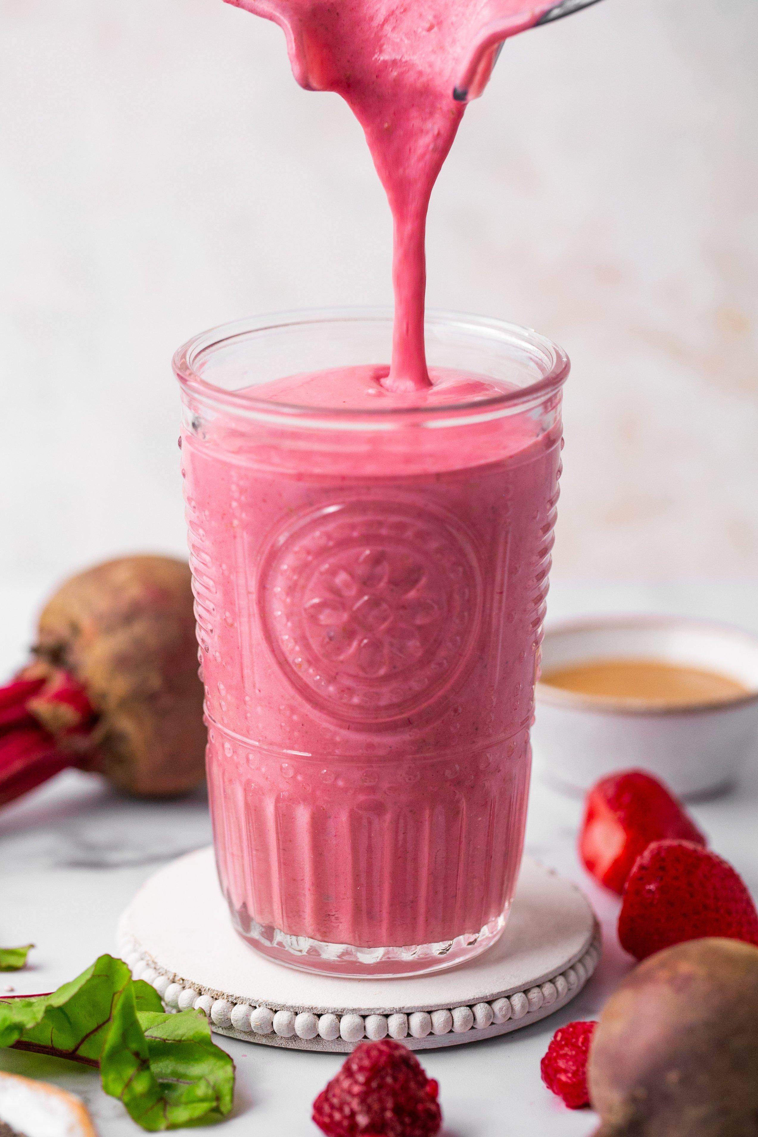 Beetroot smoothie in a glass with ingredients around it