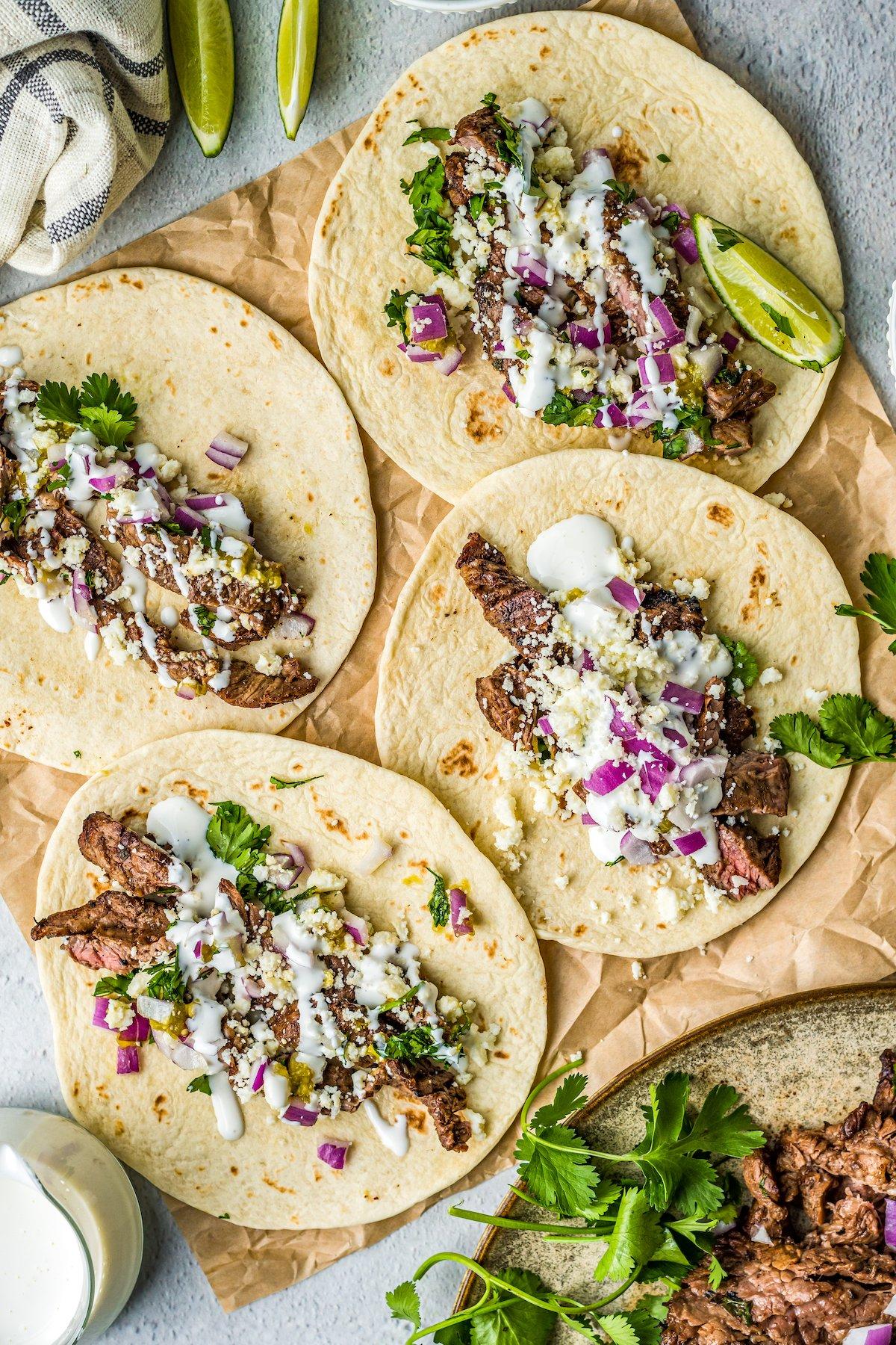 overhead shot of carne asada tacos being assembled with various toppings