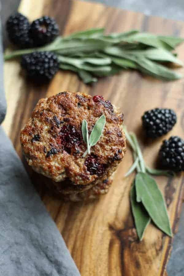 blackberries and sage leaves on a wooden cutting board