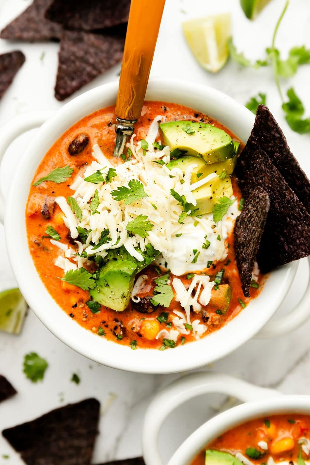 overhead shot of a steaming bowl of creamy taco chicken soup with a dollop of sour cream and fresh cilantro