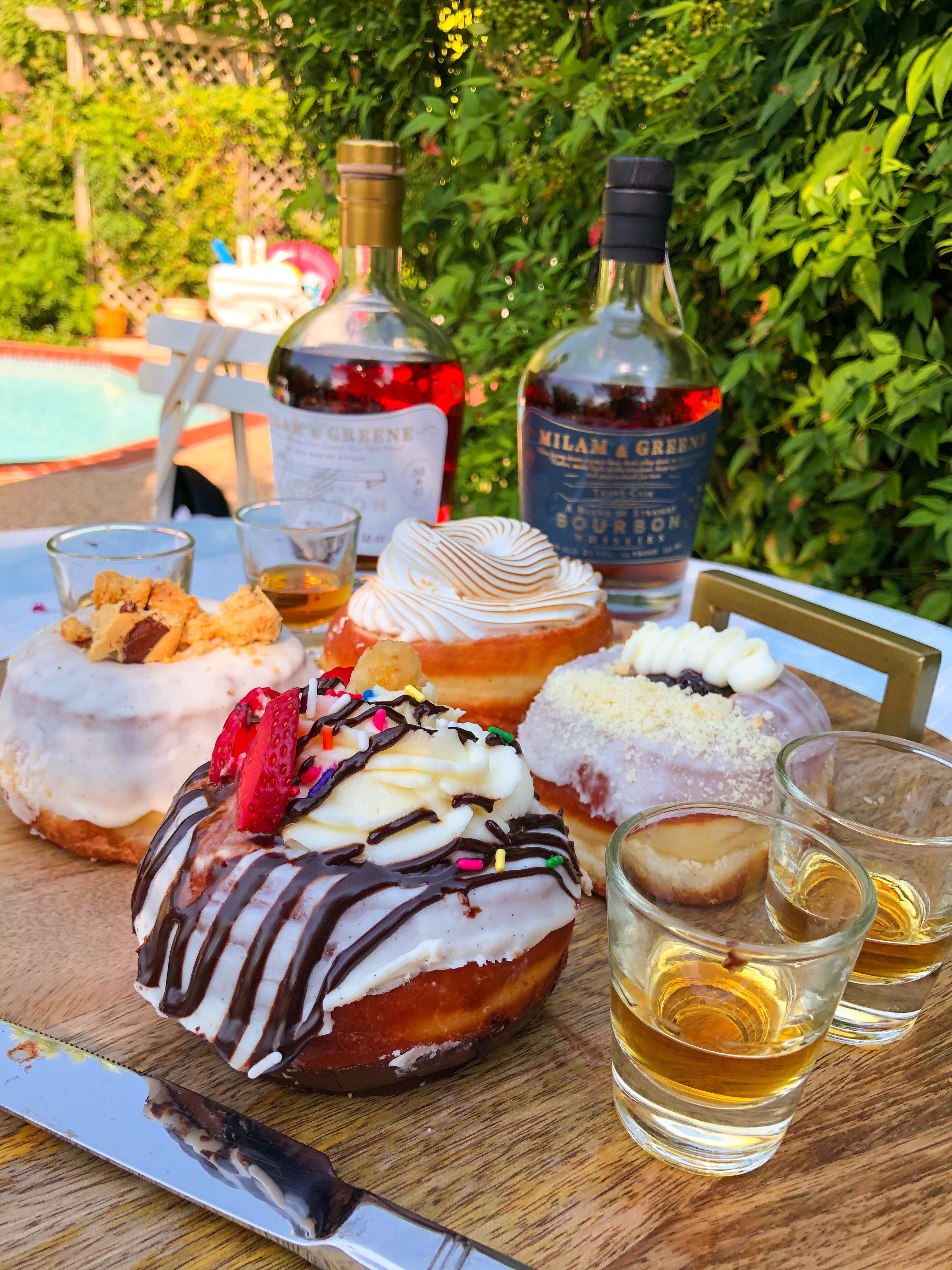 Nutmeg bourbon donuts on a wooden table, with a glass of bourbon in the background
