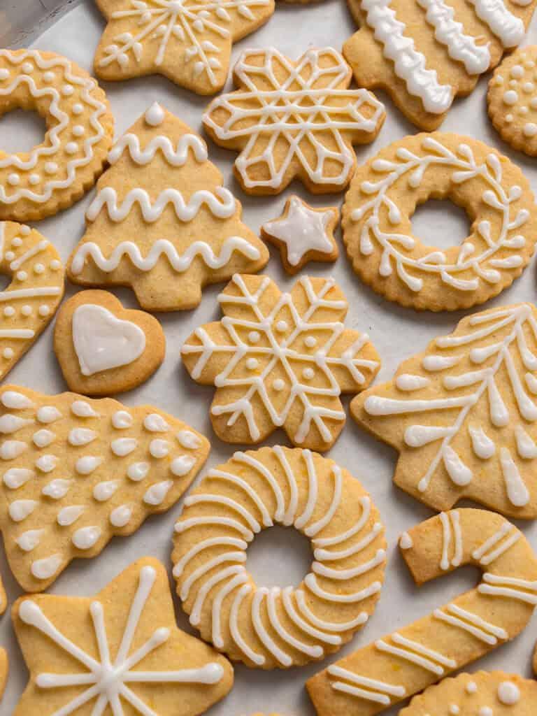 beautifully decorated vanilla sugar cookies with intricate hand-piped designs, close-up, warm lighting
