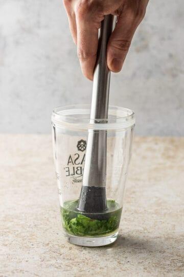 close-up of muddling basil in a cocktail shaker