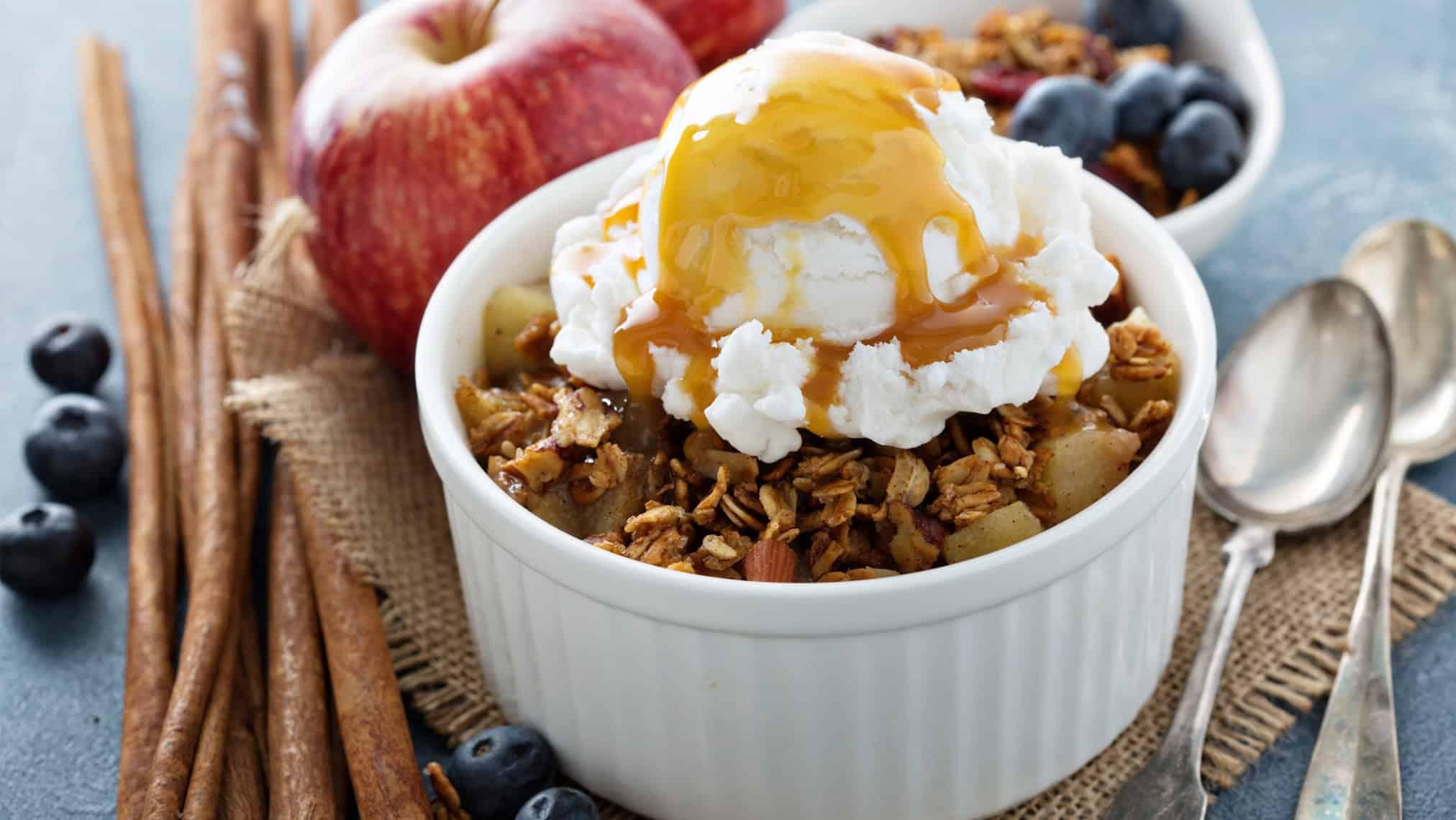 Close up of a warm apple crumble with a scoop of vanilla ice cream