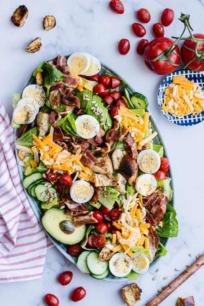 Overhead view of a Cobb salad being assembled with various ingredients