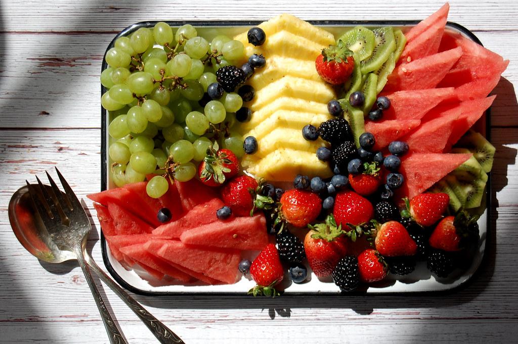 A person carefully arranging fruit on a large platter