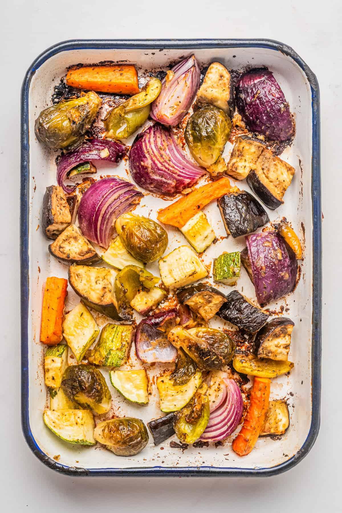 Overhead shot of various roasted vegetables on a baking sheet, ready to be added to a bowl