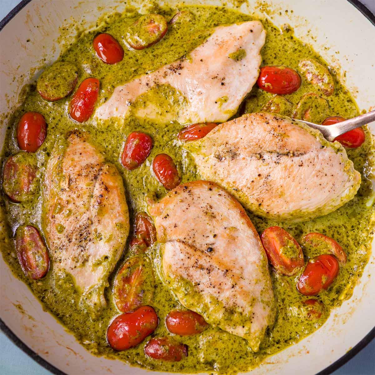 Close-up of creamy pesto chicken simmering in a pan