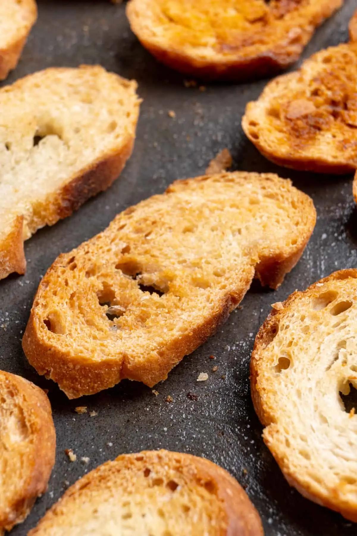 Close-up of golden brown toasted baguette slices on a cutting board