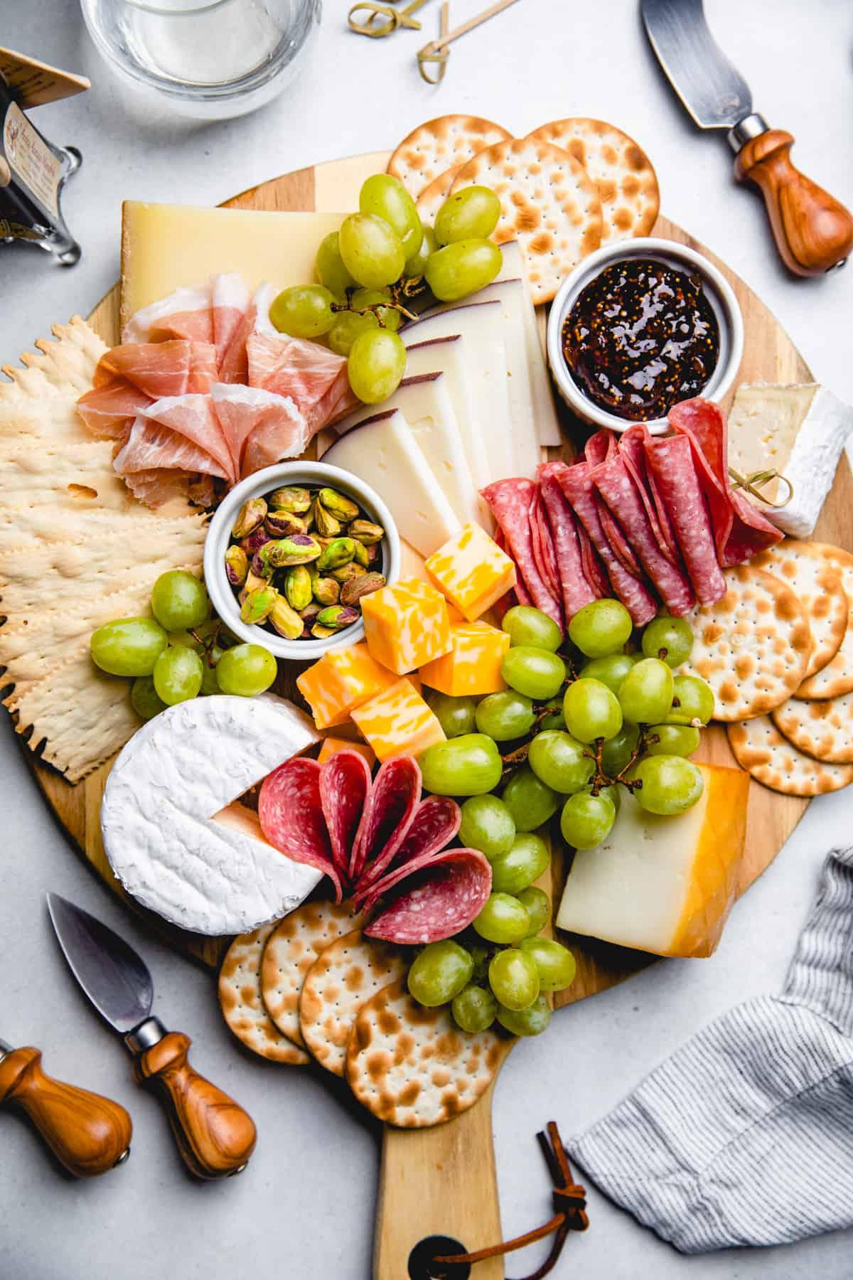 person arranging crackers and cured meats on a charcuterie board