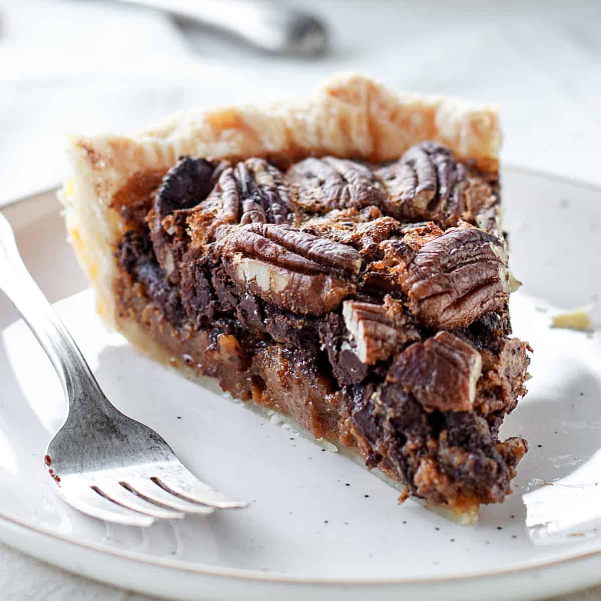 Close up of a slice of chocolate pecan pie showing the fudgy center and whole pecans