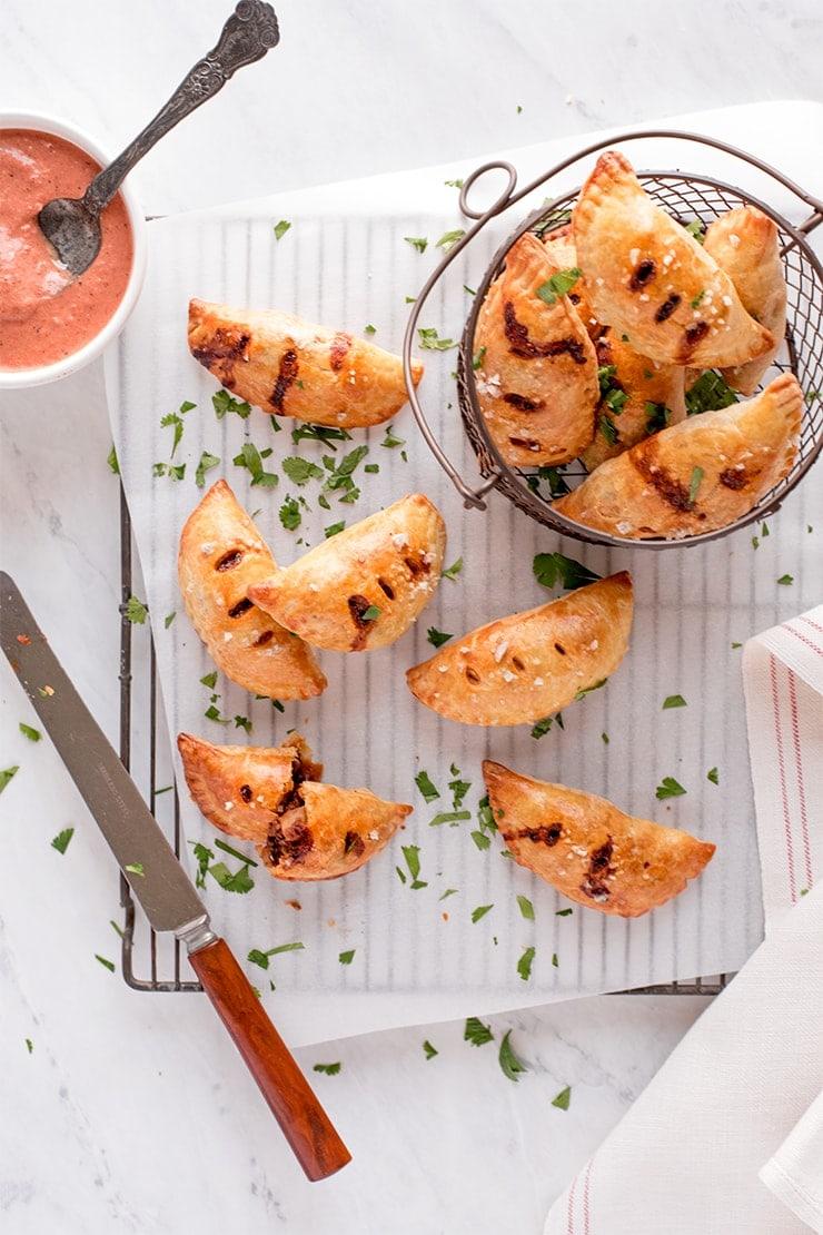 homemade empanadas with raspberry chipotle sauce served on a rustic wooden board