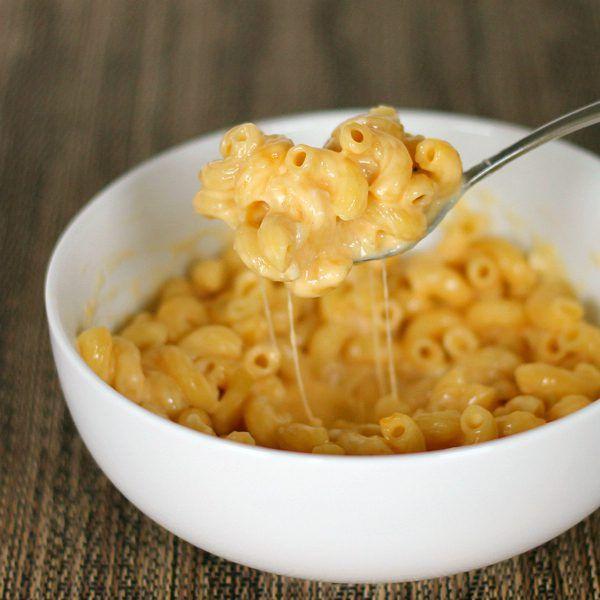 person enjoying a bowl of creamy pasta mac and cheese, cozy kitchen setting, autumn evening
