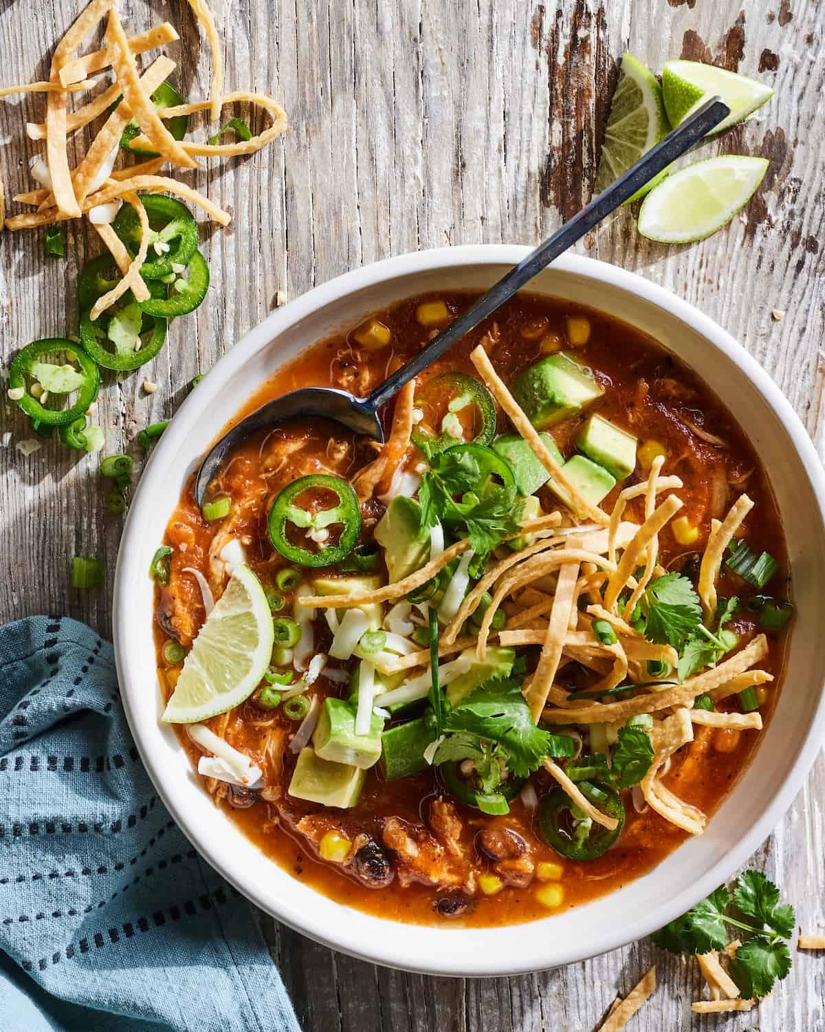 bowl of chicken tortilla soup topped with avocado and cilantro