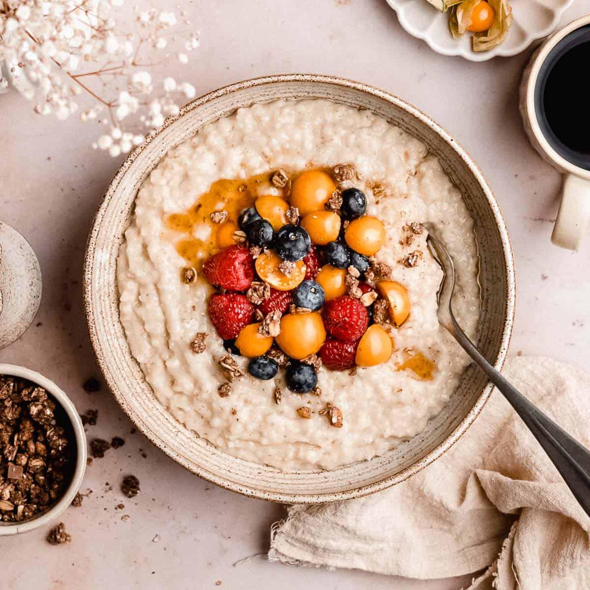 bowl of barley porridge with various toppings like berries, nuts, and seeds
