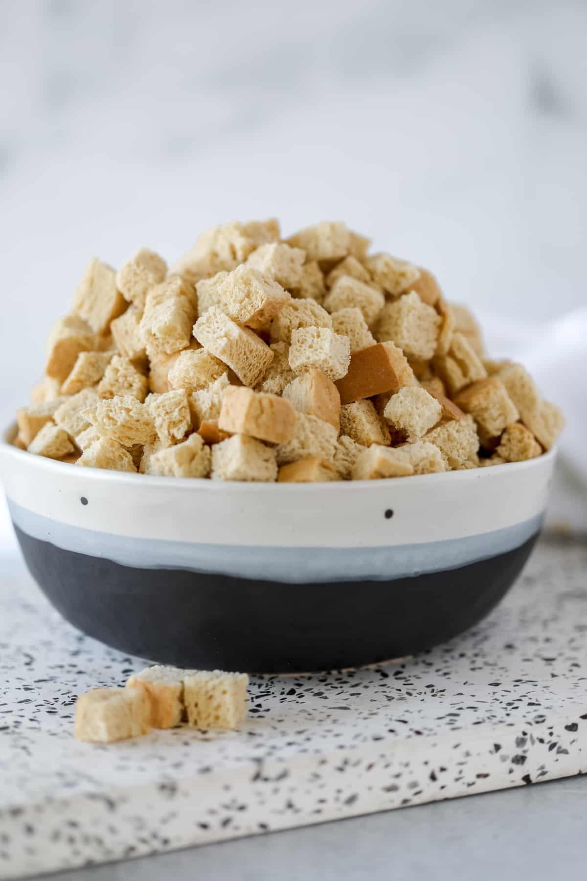 close-up of stale bread cubes being tossed in a bowl with eggs and spices