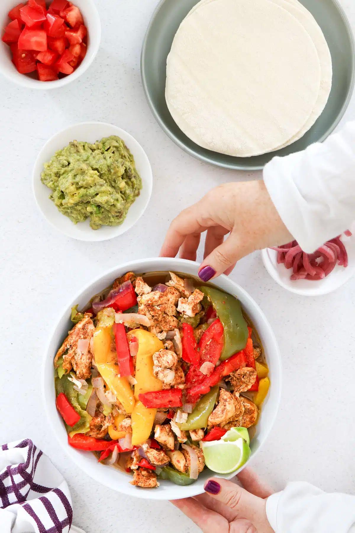 Close-up shot of an Instant Pot Chicken Fajita Rice Bowl being assembled with toppings