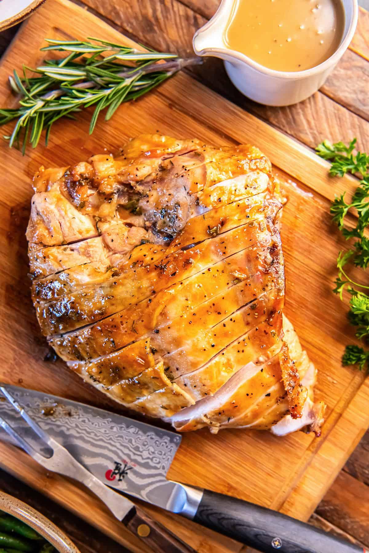 Sliced roasted turkey on a carving board with herbs