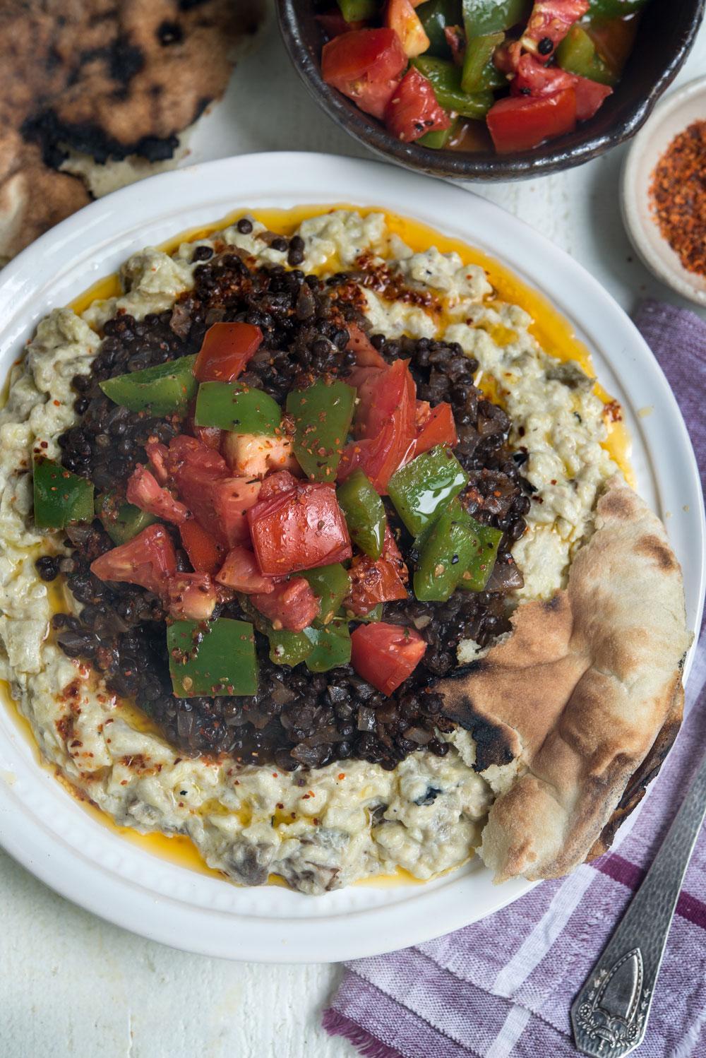 Close-up shot of smoky eggplant being added to black urad dal