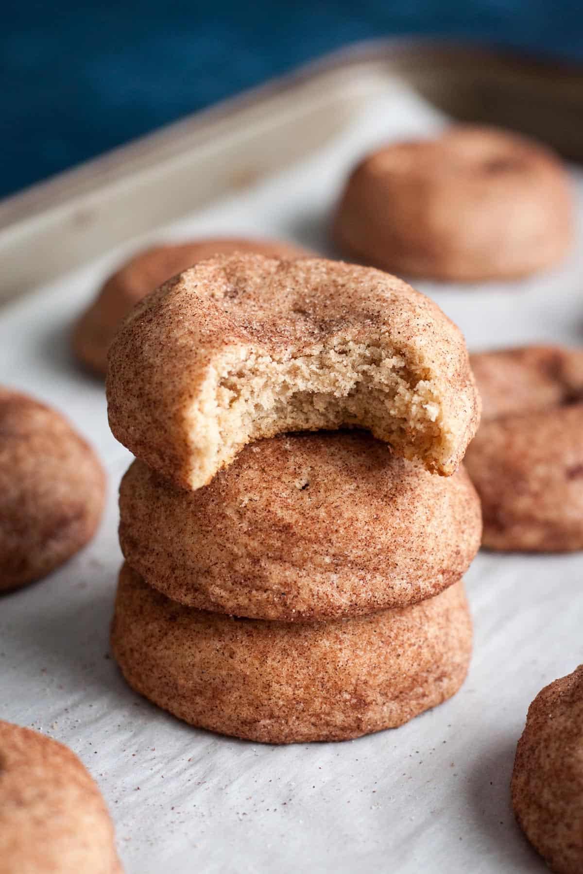stack of soft snickerdoodle cookies with a bite taken out, showing fluffy interior