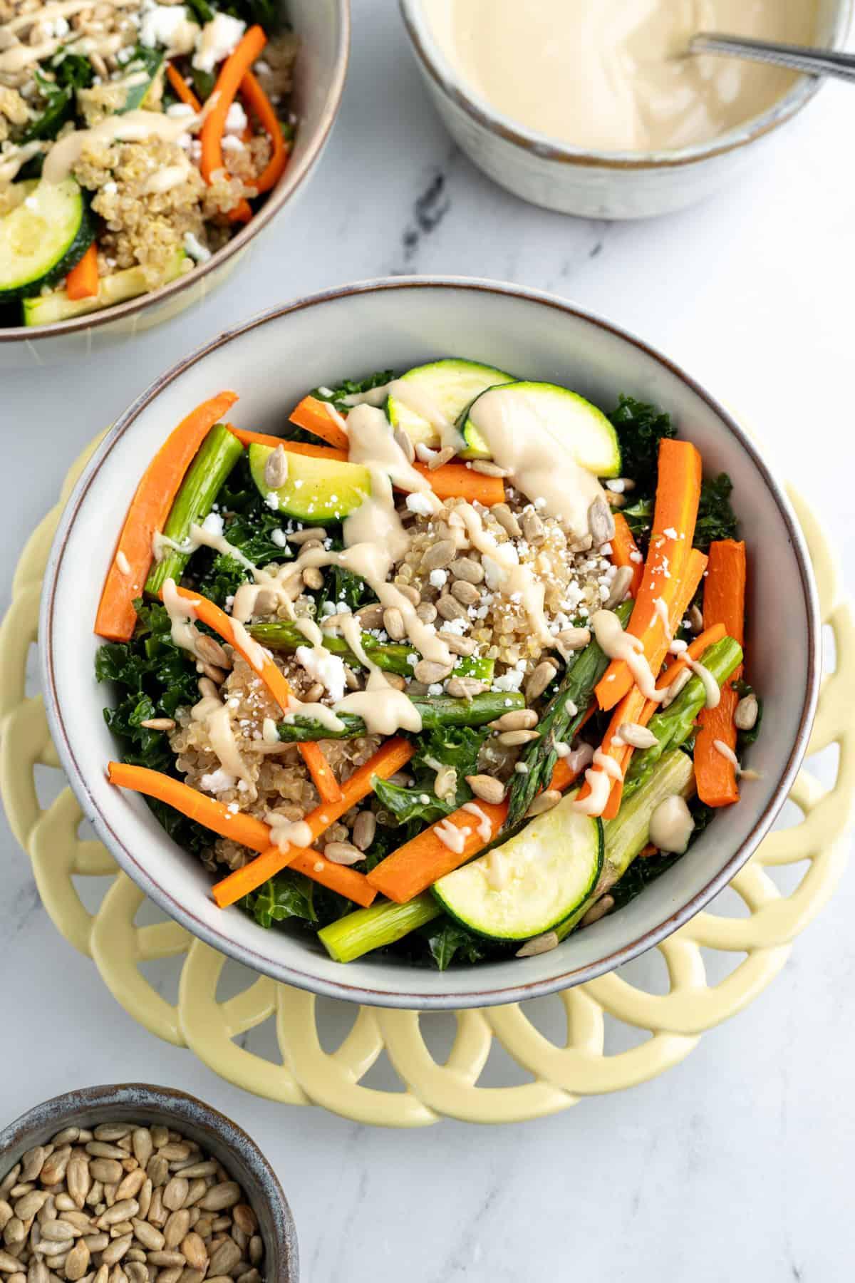 overhead shot of a prepared roasted veggie quinoa bowl with dressing drizzled