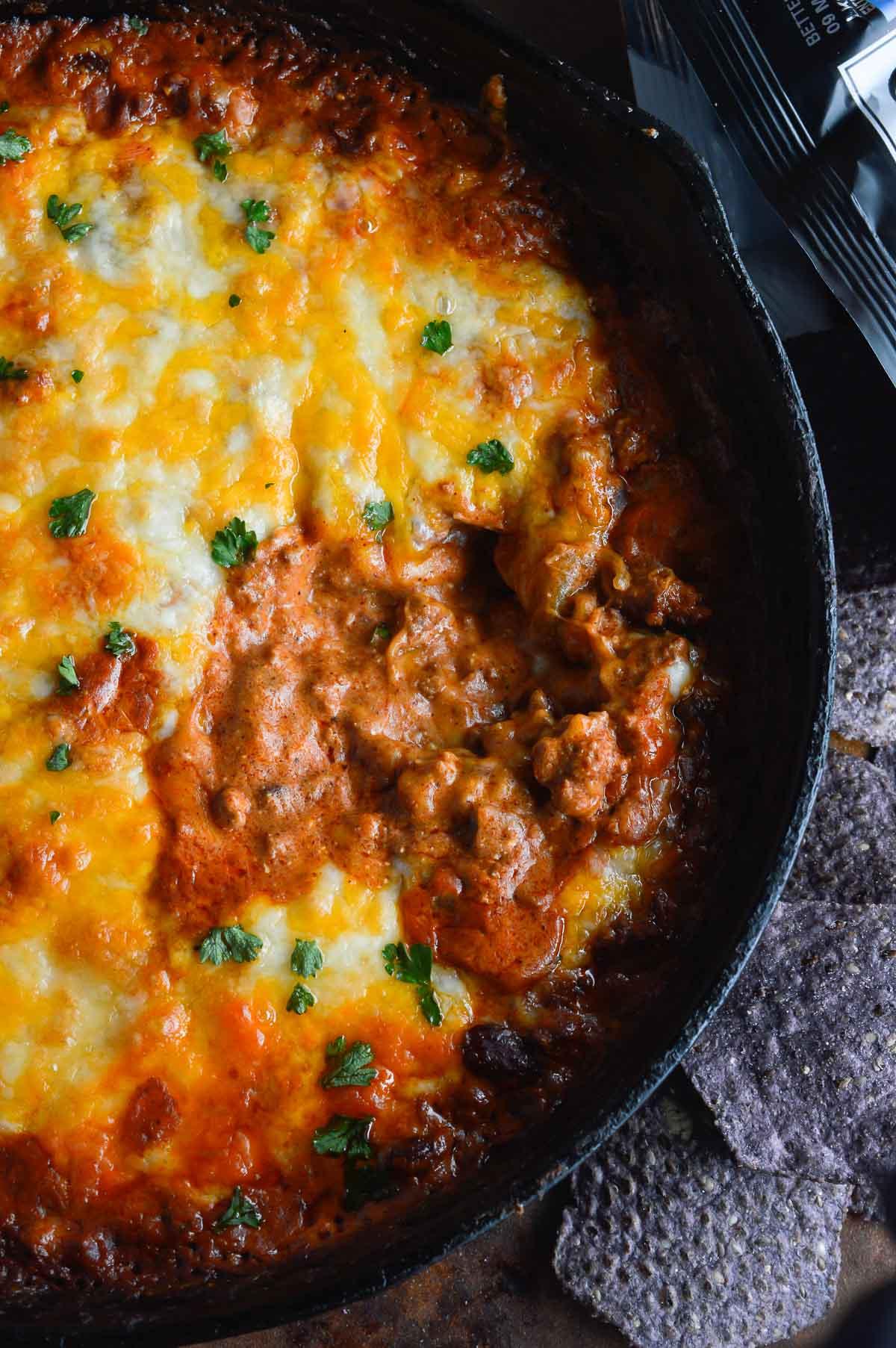 Close-up of a bubbling chili beef skillet on a stovetop with melted cheese