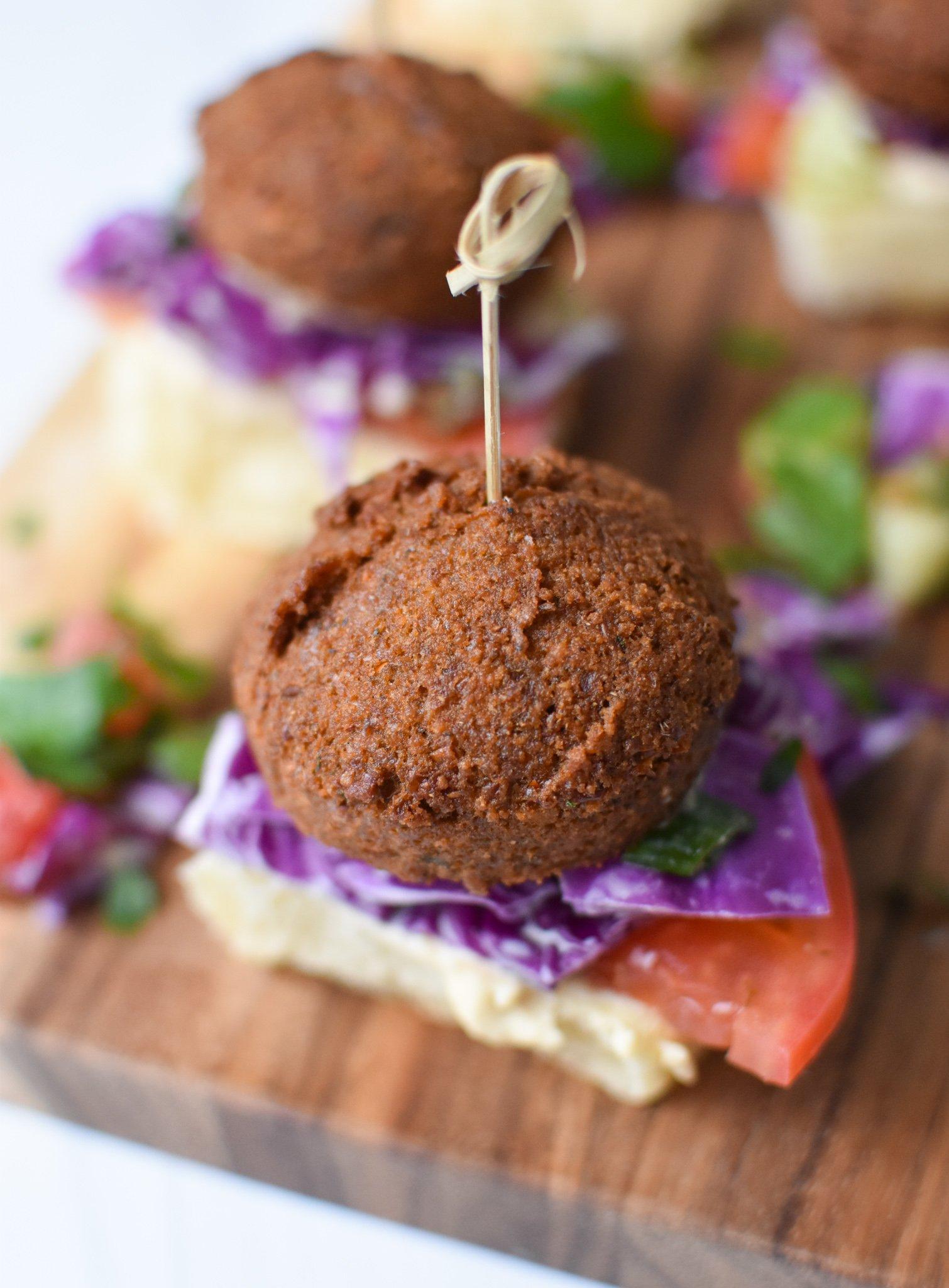 Close-up shot of delicious falafel sliders with tahini sauce, garnished with fresh herbs