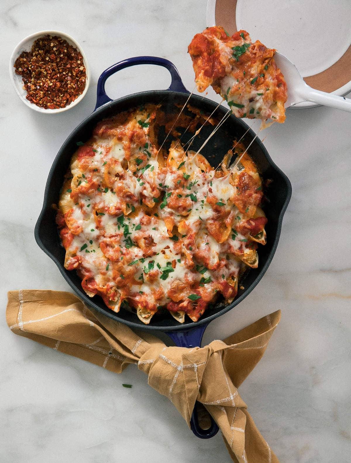 baked delicata squash and ricotta stuffed shells, garnished with fresh herbs
