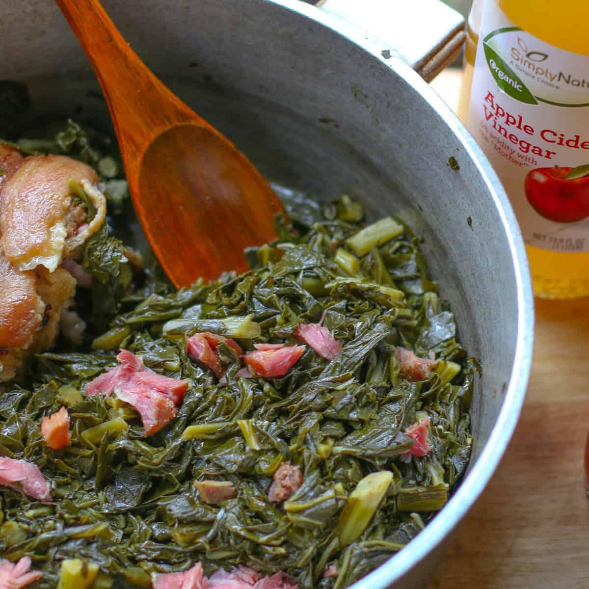 A rustic kitchen setting with a pot of collard greens simmering on the stove.