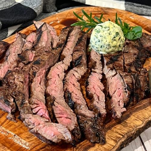grilled skirt steak being sliced against the grain on a cutting board