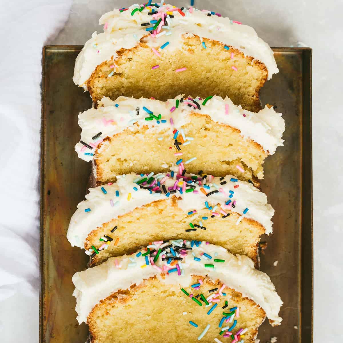 A person frosting a birthday cake loaf cake