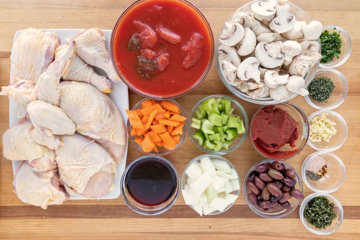Overhead shot of ingredients for Chicken Cacciatore laid out on a wooden table