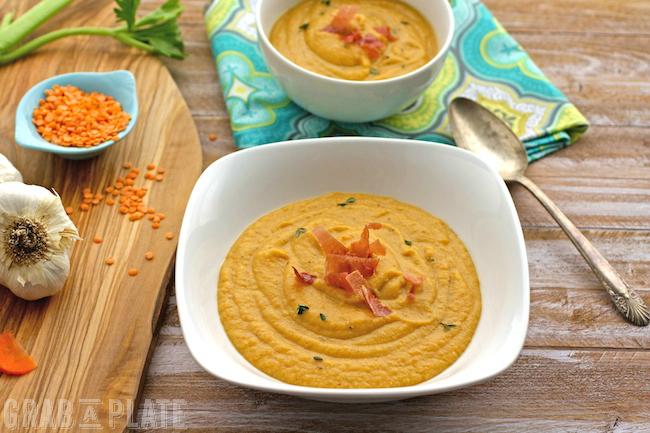 A rustic bowl of hearty lentil soup with roasted garlic cloves and fresh thyme sprigs