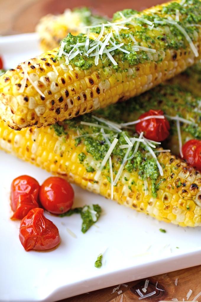 overhead shot of several ears of grilled corn with garlic scape pesto on a platter