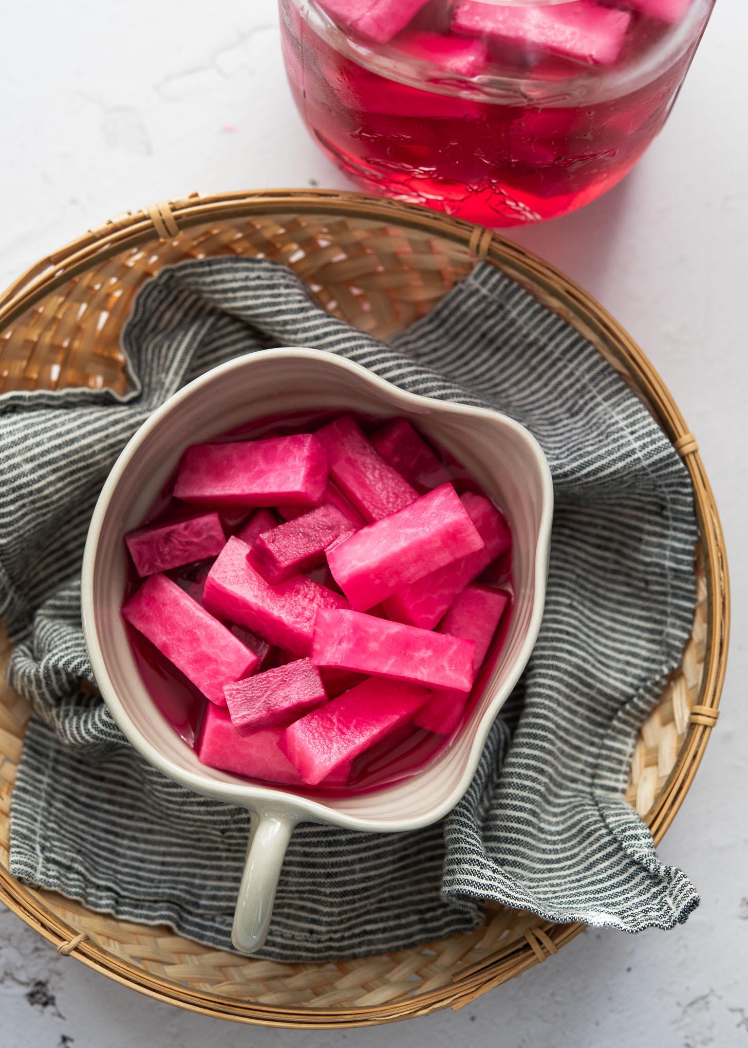 close-up of vibrant pink pickled radishes in a glass jar