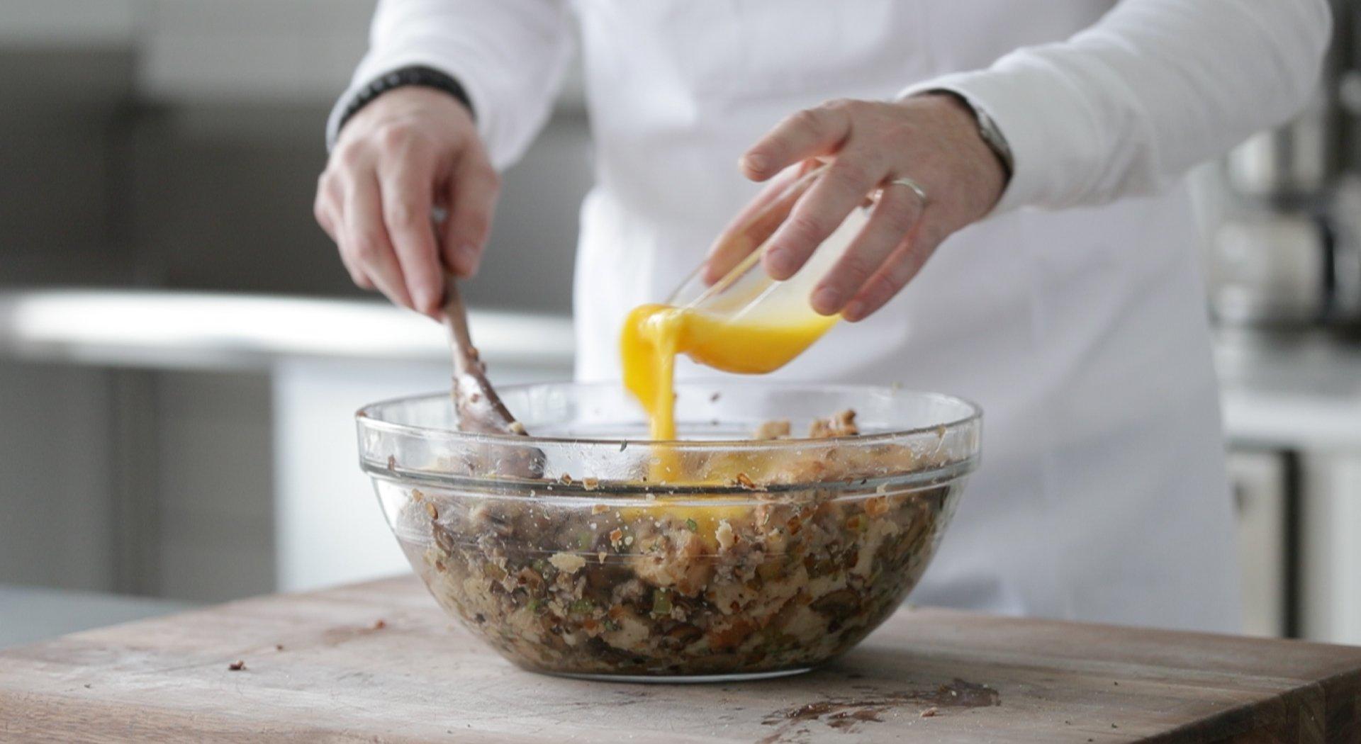 person stirring stuffing mixture in a large bowl