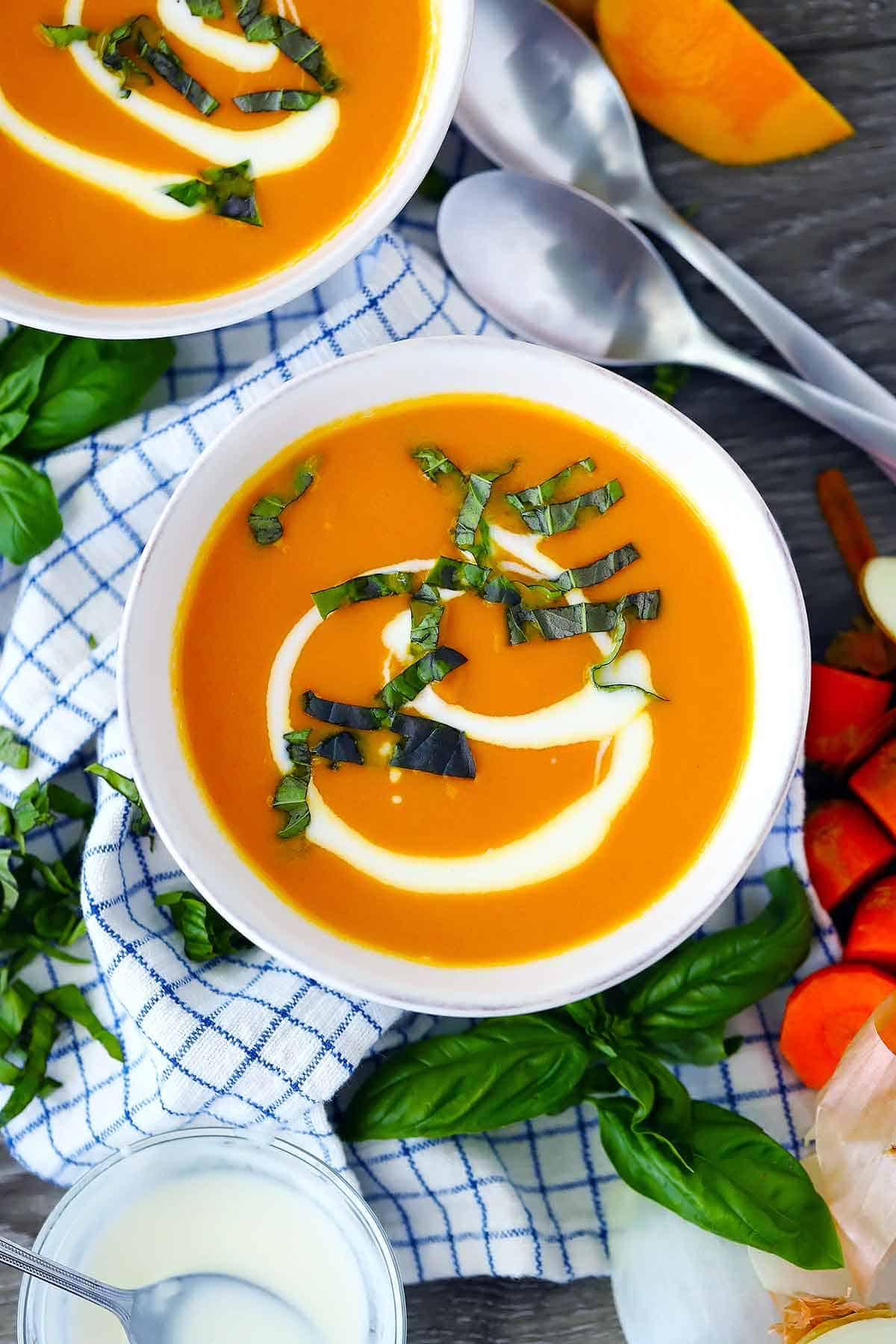 bowl of ginger carrot soup garnished with fresh herbs