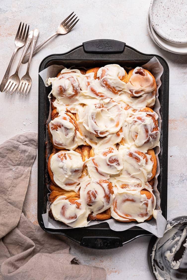 close up shot of cinnamon roll dip with cream cheese frosting with cinnamon sticks