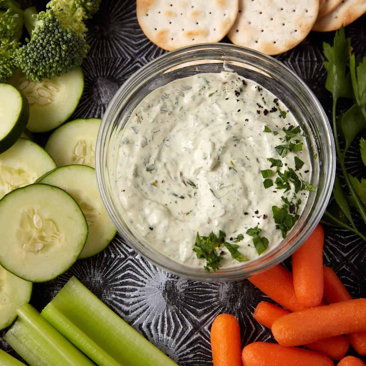 bowl of green goddess dip surrounded by fresh herbs