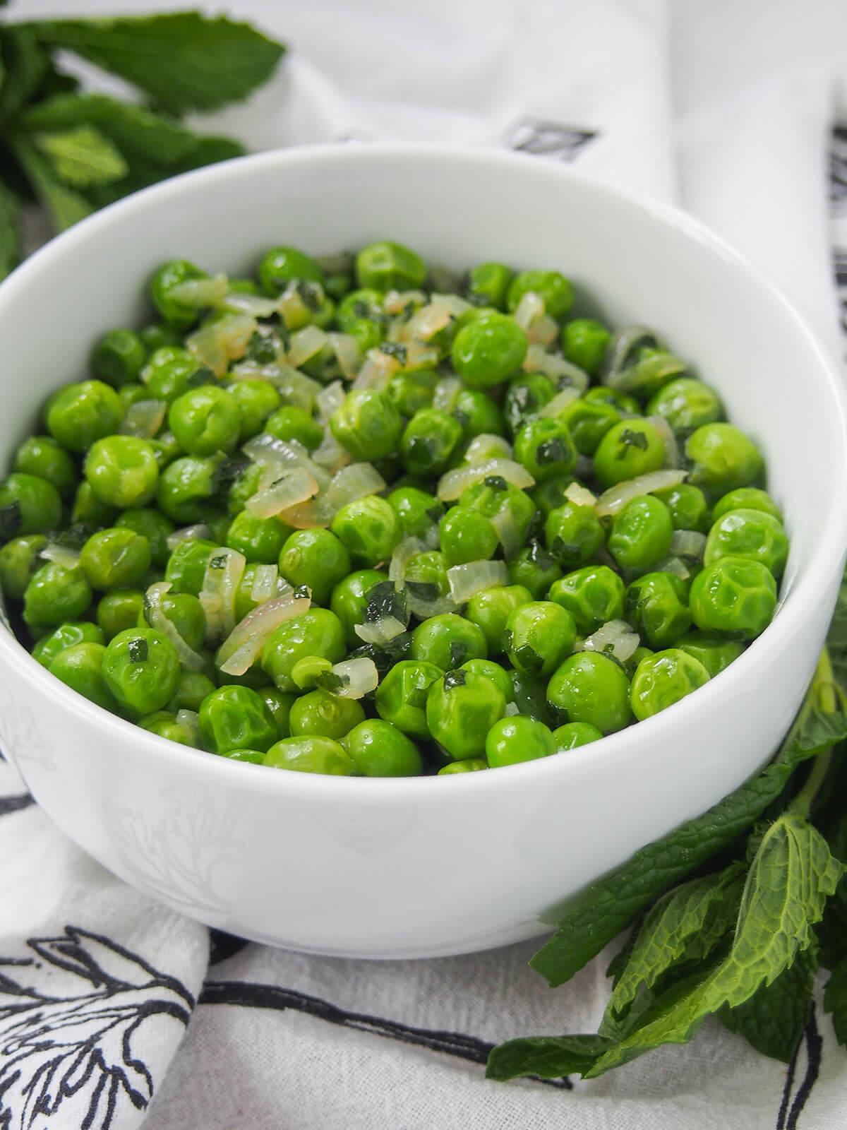 close up of steamed peas with mint and butter in a bowl