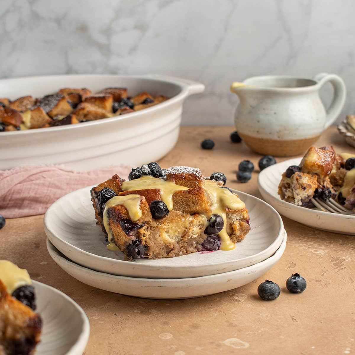 slices of bread pudding with Earl Grey tea sauce drizzled on top, on a rustic wooden table