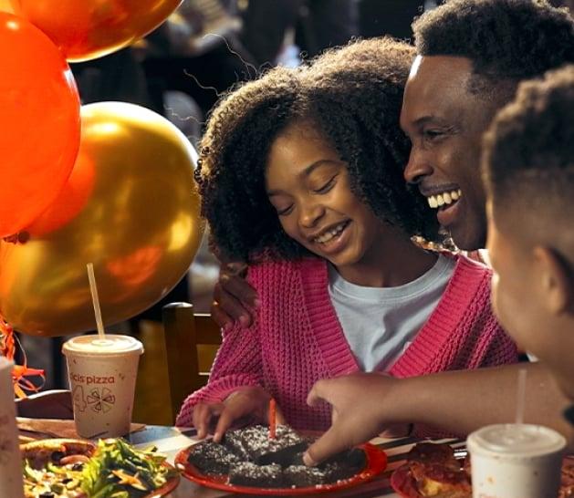 A birthday party scene with friends and family enjoying a pizza