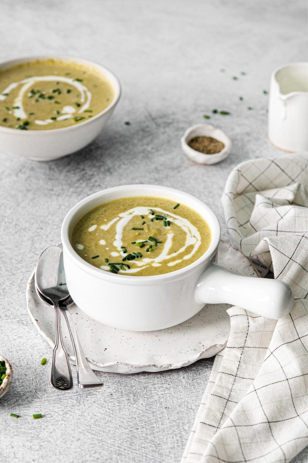 bowl of creamy asparagus soup garnished with cream and herbs
