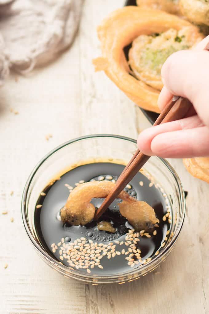 close up shot of hands dipping vegetables in tempura batter