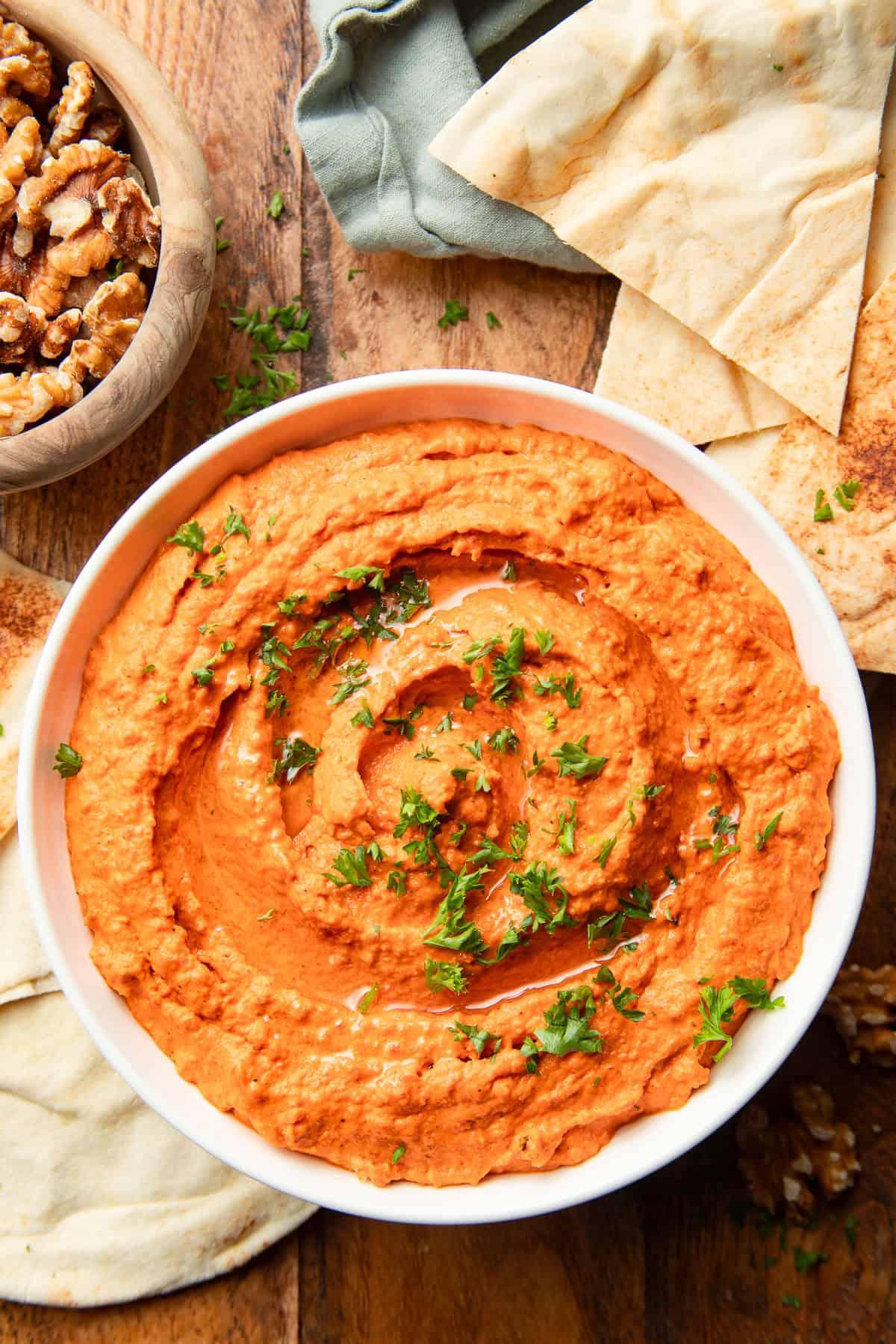 roasted red pepper and walnut hummus in a bowl with pita bread and vegetables