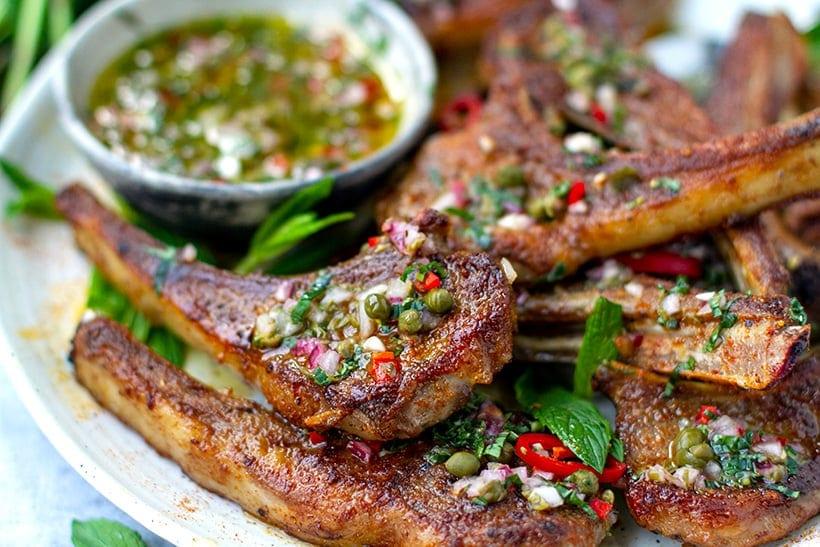 close-up shot of a skillet with basil-crusted lamb chops being seared