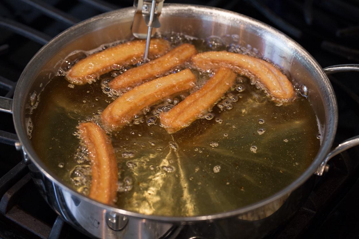 churros being fried in a pan