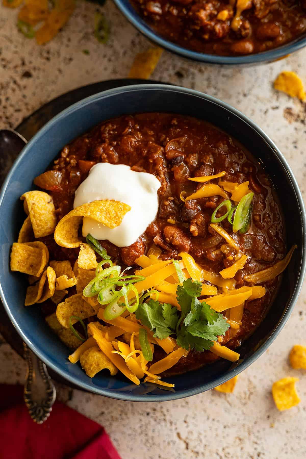 a bowl of slow cooker chili topped with shredded cheese and sour cream