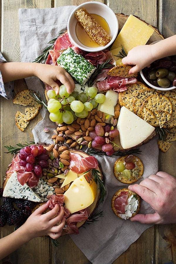 overhead view of charcuterie board with a hand reaching for a cracker