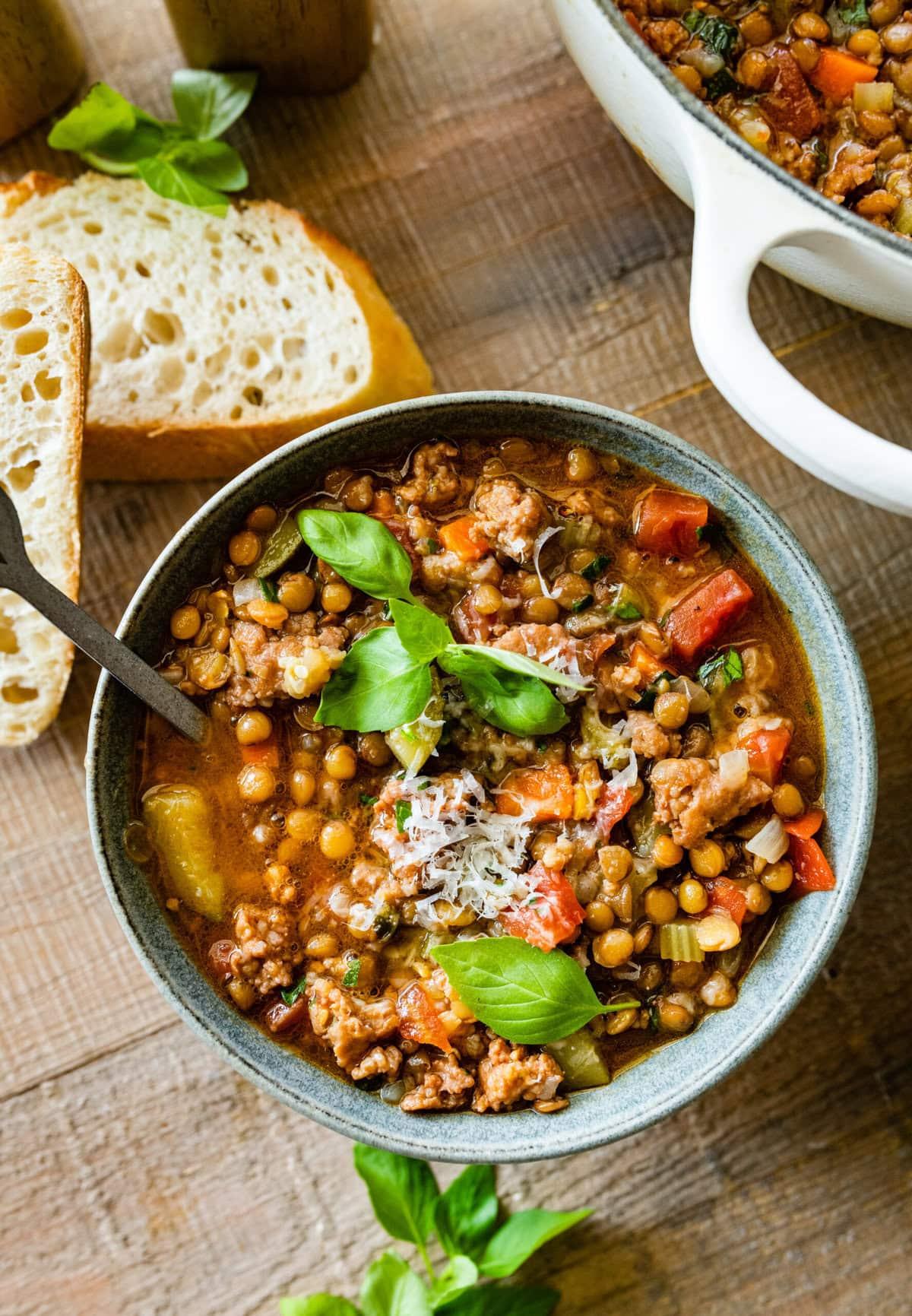 a bowl of hearty one-pot lentil soup with sausage, garnished with fresh herbs